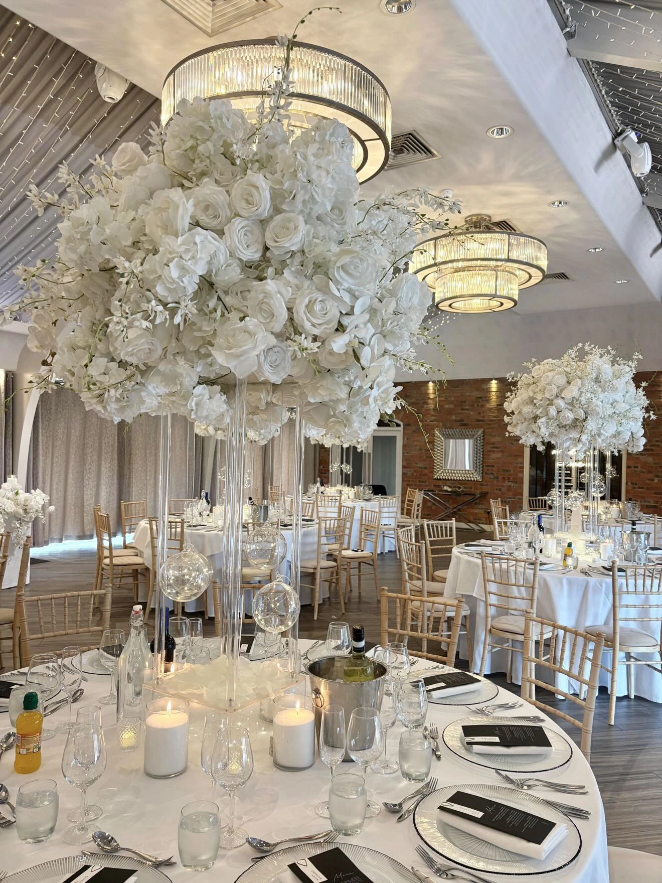 White floral centrepieces and candlelit tables at Joe and Ella’s reception